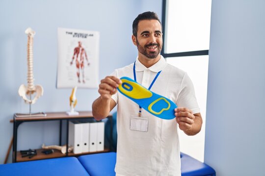 Young hispanic man podiatrist holding insole at podiatry center