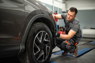 Obraz na płótnie Canvas the mechanic checks the tires in the service station