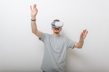 Futuristic man wearing virtual reality glasses interacts with the air in an isolated gray background.