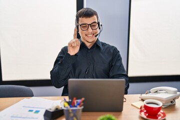 Young arab man wearing call center agent headset smiling with an idea or question pointing finger...