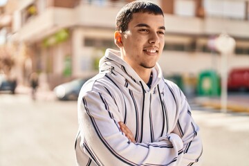 Young man smiling confident standing with arms crossed gesture at street