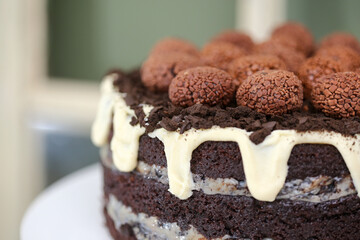 Um irresistível bolo de chocolate ao leite, com deliciosa cobertura de chocolate branco, decorado com encantadoras flores de papel, embelezando uma festa infantil cheia de alegria e diversão.