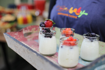 Deliciosos potinhos de vidro com iogurte natural coberto com frutas vermelhas, uma opção refrescante e saudável para aproveitar em eventos descontraídos.