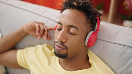 Obraz premium African american man listening to music relaxed on sofa at home