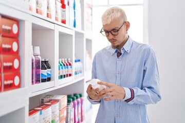 Young caucasian man customer looking pills bottle at pharmacy