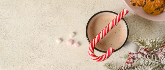 Fototapeta na wymiar Cup of tasty hot chocolate with candy cane on light background, top view. Banner for design