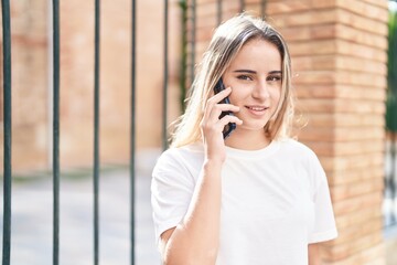 Young blonde woman smiling confident talking on the smartphone at street