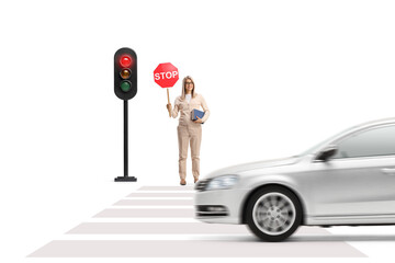Young woman holding a book and a stop sign and standing near traffic lights