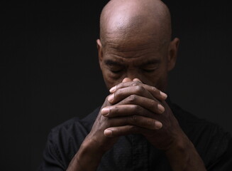 man praying to god with hands together Caribbean man praying stock photo	