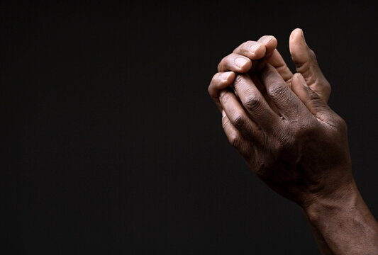 man praying to god with hands together on grey black background stock image stock photo	