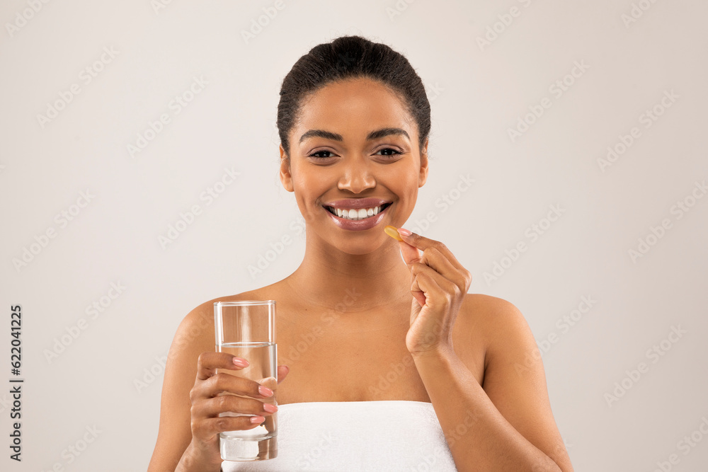 Wall mural Happy young african american woman taking beauty pill