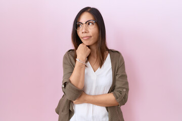 Fototapeta premium Middle age chinese woman wearing glasses over pink background with hand on chin thinking about question, pensive expression. smiling with thoughtful face. doubt concept.