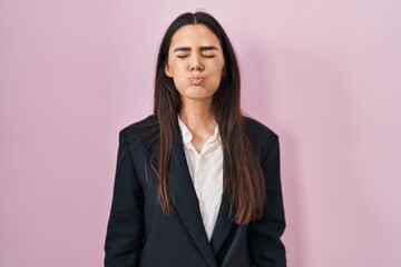 Young brunette woman wearing business style over pink background puffing cheeks with funny face. mouth inflated with air, crazy expression. - obrazy, fototapety, plakaty