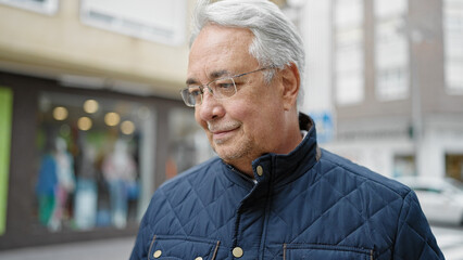 Middle age man with grey hair standing with serious expression at street