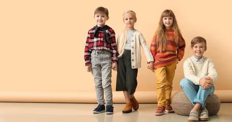 Cute little children in stylish autumn clothes near beige background. Banner for design