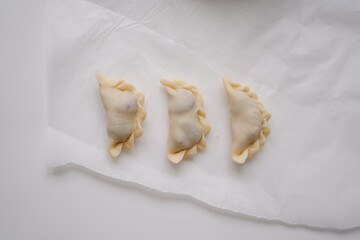 Traditional Ukrainian recipes. Close-up, top view of three raw Ukrainian traditional varenyki ready for cooking.