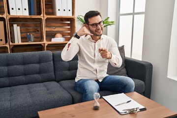 Young hispanic man with beard working at consultation office smiling doing talking on the telephone...