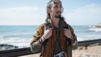 Tuinposter Young hispanic man tourist wearing backpack at seaside © Krakenimages.com