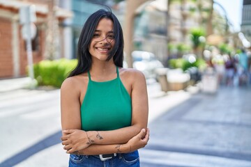 Young hispanic woman smiling confident standing with arms crossed gesture at street