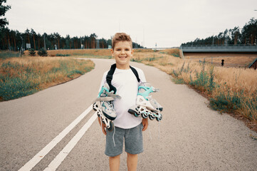 Smiling boy 7 years old carries roller skates