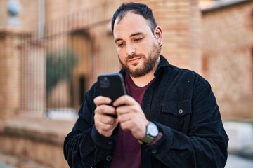 Young hispanic man using smartphone at street