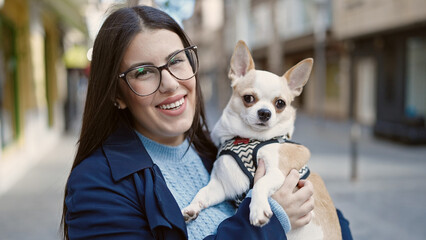 Young hispanic woman with chihuahua dog smiling confident at street