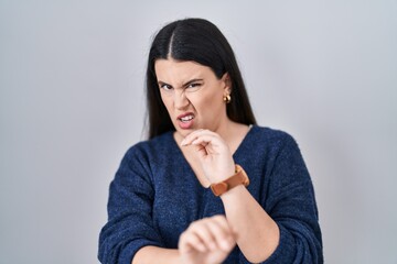 Young brunette woman standing over isolated background disgusted expression, displeased and fearful doing disgust face because aversion reaction.