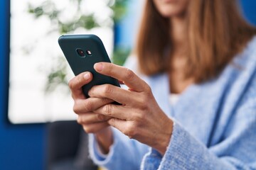 Young woman using smartphone sitting on sofa at home