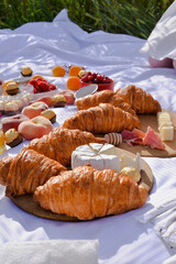 Breakfast, picnic with croissants, cheese, honey and fruits on the white tablecloth