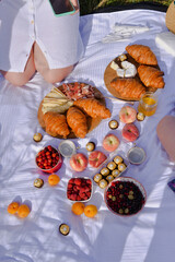 Breakfast, picnic with croissants, cheese, honey and fruits on the white tablecloth