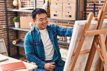 Young chinese man artist drawing on canvas at art studio