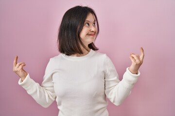 Woman with down syndrome standing over pink background showing middle finger doing fuck you bad...