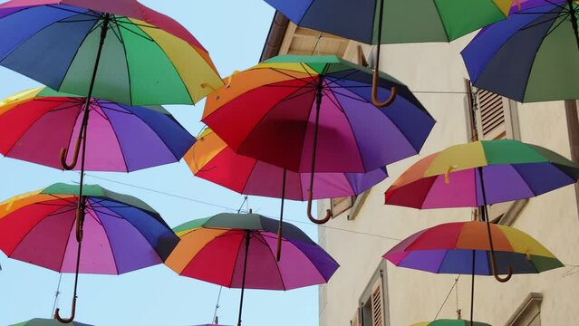 Rainbow umbrellas on blue sky background. Many colorful umbrellas, street decoration for festivals. Concept diversity