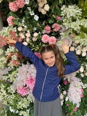 Pretty young girl smiling at the camera surrounded by flowers 