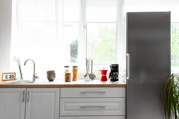 Interior of kitchen with stylish fridge, counters and window