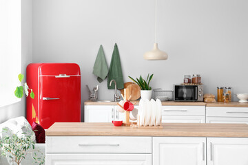 Interior of light kitchen with red fridge and counters