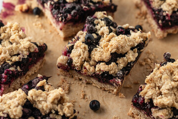 Vegan baked oatmeal squares with fresh blueberry on beige parchment paper