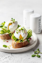 Poached egg sandwich with cucumber and microgreens. Healty breakfast bruschetta on white background. Keto diet close up