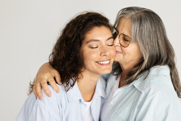 Fototapeta na wymiar Happy european elderly woman hugging, kissing millennial lady