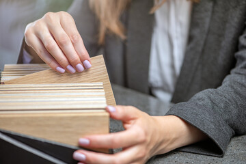 Samples of wood in hands close-up. A woman designer selects wood samples from a collection for a project.
