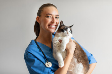 Portrait Of Happy Veterinarian Doctor Woman Holding Cat, Gray Background