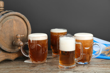 Mugs of cold beer and wooden barrel on table. Oktoberfest celebration