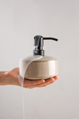 Hand with liquid soap on grey background