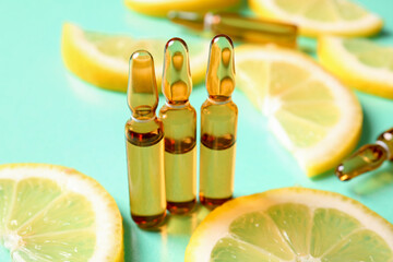 Ampoules with vitamin C and lemon slices on turquoise background