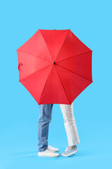 Young couple with umbrella on blue background