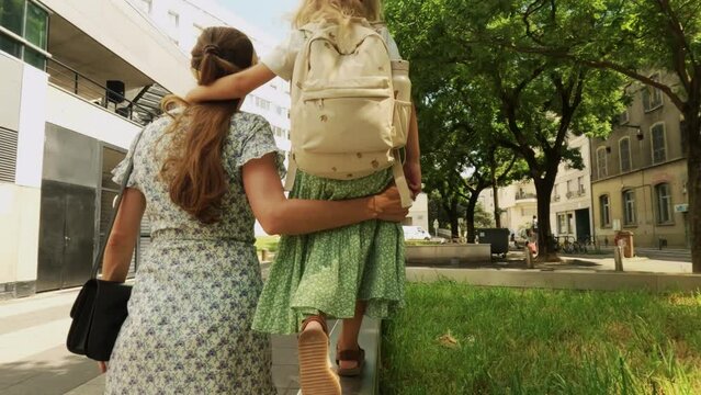 Mother and her little girl walk together in the city, slow motion