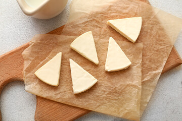 Board with triangles of tasty processed cheese and milk on light background, closeup