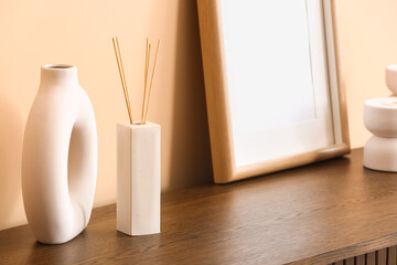 Bottle of reed diffuser on table near beige wall in room, closeup