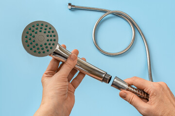Woman hands connecting the hose to a shower head. Female hands hold hand held showerhead and...