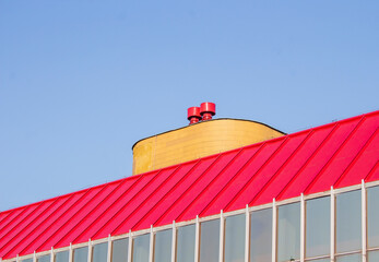 Red Roof with chimney. Industrial Building Closeup. Red Blue Yellow.